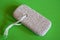 Skincare Tool Display. Pumice stone with string, presented on vibrant green, highlighting its exfoliating texture