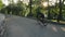 Skinny athletic cyclist ascending the hill in the park. Cyclist downhill in park. Road cyclist. Slow motion