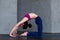 Skinny flexible female yogini bending backwards doing stretching exercises on floor in a room