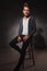 Skinny guy posing in studio while sitting with hand in pocket