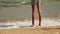Skinny legs of young lady who spend summer vacation time strolling on white sandy beach