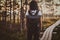 Skinny woman is hiking by the wooden path in the middle of lush pine forest.