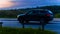 Skoda Kodiaq driving on the country road at dusk. Side view of SUV in motion on the background of evening sunset sky