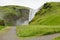 Skogafoss waterfall in Iceland hidden behing a rocky mountain with pavements for tourists