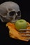 Skull circling the table apple with his arm and bony hand