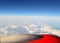 The sky from airplane window. View from the high. View on horizon. Red airplane wing. Sky travel picture with space for text