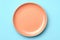 Sky Blue Monochrome Plate On Peach Background, Top View. Generative AI