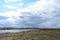 Sky, clouds. Hill. Grass on the banks of the river. Forest in the distance. Village on the river Bank. Rural view