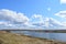 Sky, clouds. Meandering river. Grass on the low banks of the river. Forest in the distance. Rural view