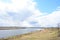 Sky, clouds. Meandering river. Grass on the low banks of the river. Forest in the distance. Rural view