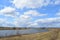 Sky, clouds. River. Boundless field. In the distance, the forest and the village. Rural view of nature