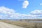 Sky, clouds. Road. Village on the banks of the river. Fields of young grass. Agricultural