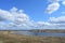 Sky, clouds. A village on the banks of the Kostroma river. Forest in the distance. Grass fields. Agricultural