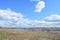 Sky, clouds. A village on both sides of the Kostroma river. Forest in the distance. Fields of young grass. Agricultural