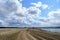 Sky, clouds. Winding road. River. Field. Forest in the distance. Rural view