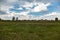 A sky with cumulus clouds over an uncultivated field in the countryside. Horizontal orientation.