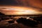 Sky with deep hanging storm clouds and wet sludge during low tide swathed in yellow and red bright light during sunset