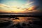 Sky with deep hanging storm clouds and wet sludge during low tide swathed in yellow and red bright light during sunset