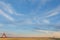 Sky with multicolored, fluffy, tender cirrus clouds, yellow field, granary and silver barns for grain