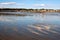 The sky is reflected in the shallow, rippled waters of a beach