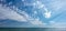 Sky with small clouds over the sea with a breakwater and a beacon