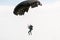 Skydiver and black parachute on the sky background