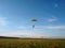 A skydiver with a bright multicolored parachute flies against the background of a blue sky