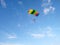 A skydiver with a bright multicolored parachute flies against the background of a blue sky