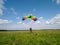A skydiver with a bright multicolored parachute flies against the background of a blue sky