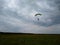 A skydiver with a bright multicolored parachute flies against a gray overcast sky