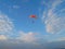 A skydiver with a bright orange parachute flies against a blue sky