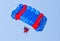 Skydiver descends by parachute in blue sky