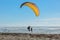 A skydiver landing on a beach of Oregon coast greeted by a random person