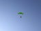 Skydiver before landing with a multicolored parachute on a blue sky background