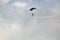 Skydiver on a para sail with red white and blue smokers.