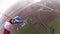 Skydiver parachuting in cloudy sky above green field, river. Height. Landscape.