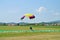 Skydiver skydiving & landing with colourful purple rose yellow parachute on parachuting cup