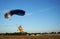 Skydiver under a small blue canopy of a parachute is landing on