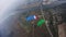 Skydivers with colorful parachutes balance in sky over green field. Extreme.