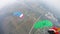 Skydivers with colorful parachutes fly over field. Extreme active sport. Tandem
