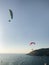 Skydivers fly over the sea against the backdrop of a beautiful sunset, islands and yachts.