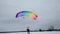 Skydivers with multi-colored parachutes land on a background of cloudy sky and snow