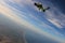 Skydiving. Freedom as a way of life. Parachutist performs an acrobatic trick in the air. Parachutist in green suit