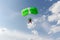 Skydiving. A green parachute and red skydiver are in the sky.