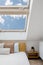 Skylight window over comfort bed in white bedroom interior