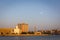 Skyline of Deira, Dubai during sunset with Dubai Creek, mosque minaret and crescent moon in the sky.