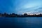 A skyline of Montreal Old Port and Downtown at the twilight blue hour. Foreground is Saint Laurent river