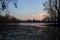 Skyline of a town seen from the distance over a lake at sunset framed by trees