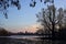 Skyline of a town seen from the distance over a lake at sunset framed by trees