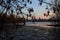 Skyline of a town seen from the distance over a lake at sunset framed by trees